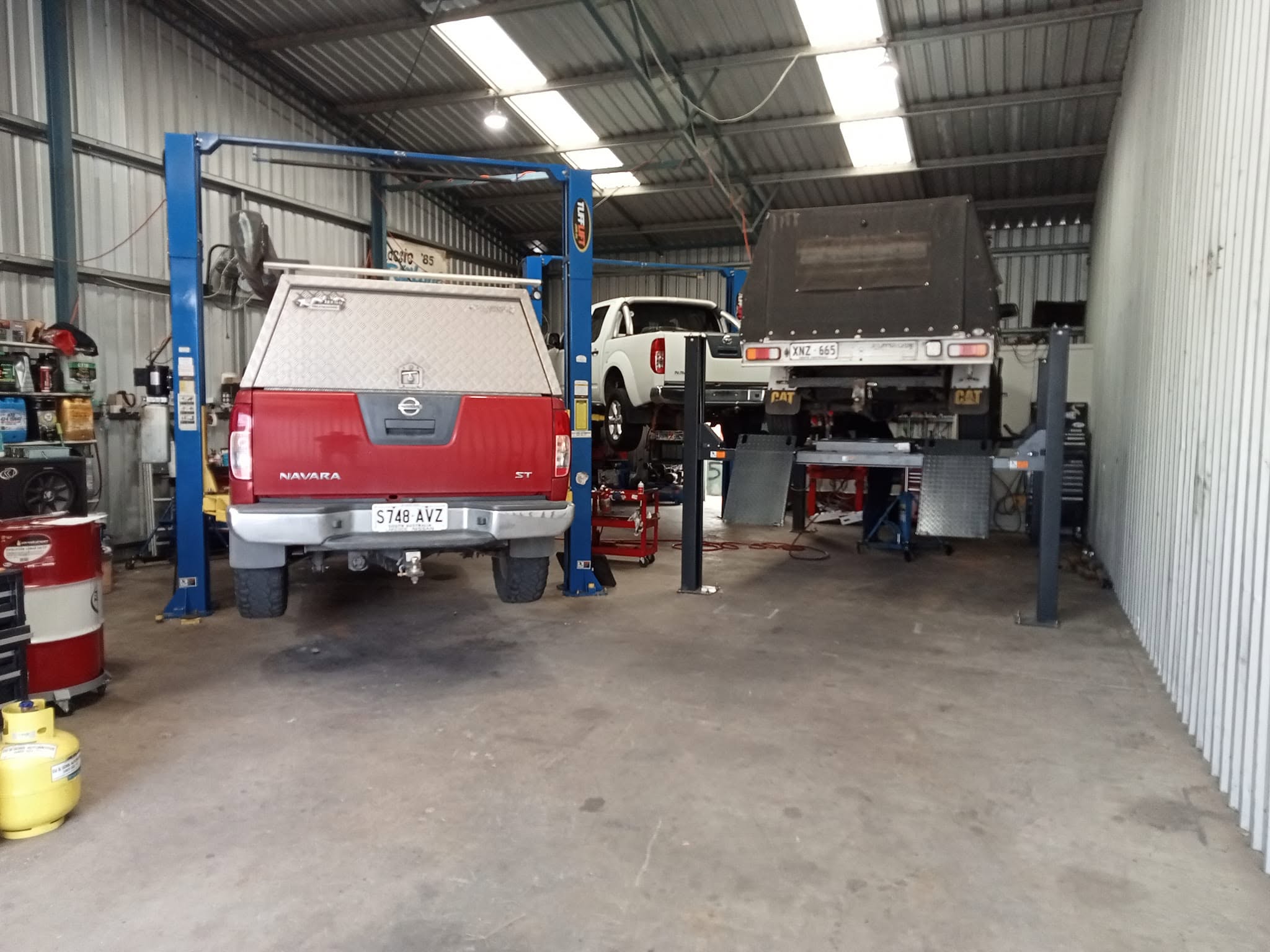 Vehicles being serviced on hoists inside the DJ and Sons Automotive workshop